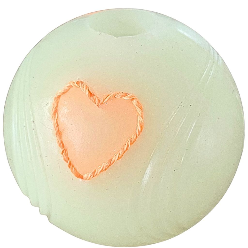 Off white rubber dog ball with an embroidered orange heart sewn into the rubber