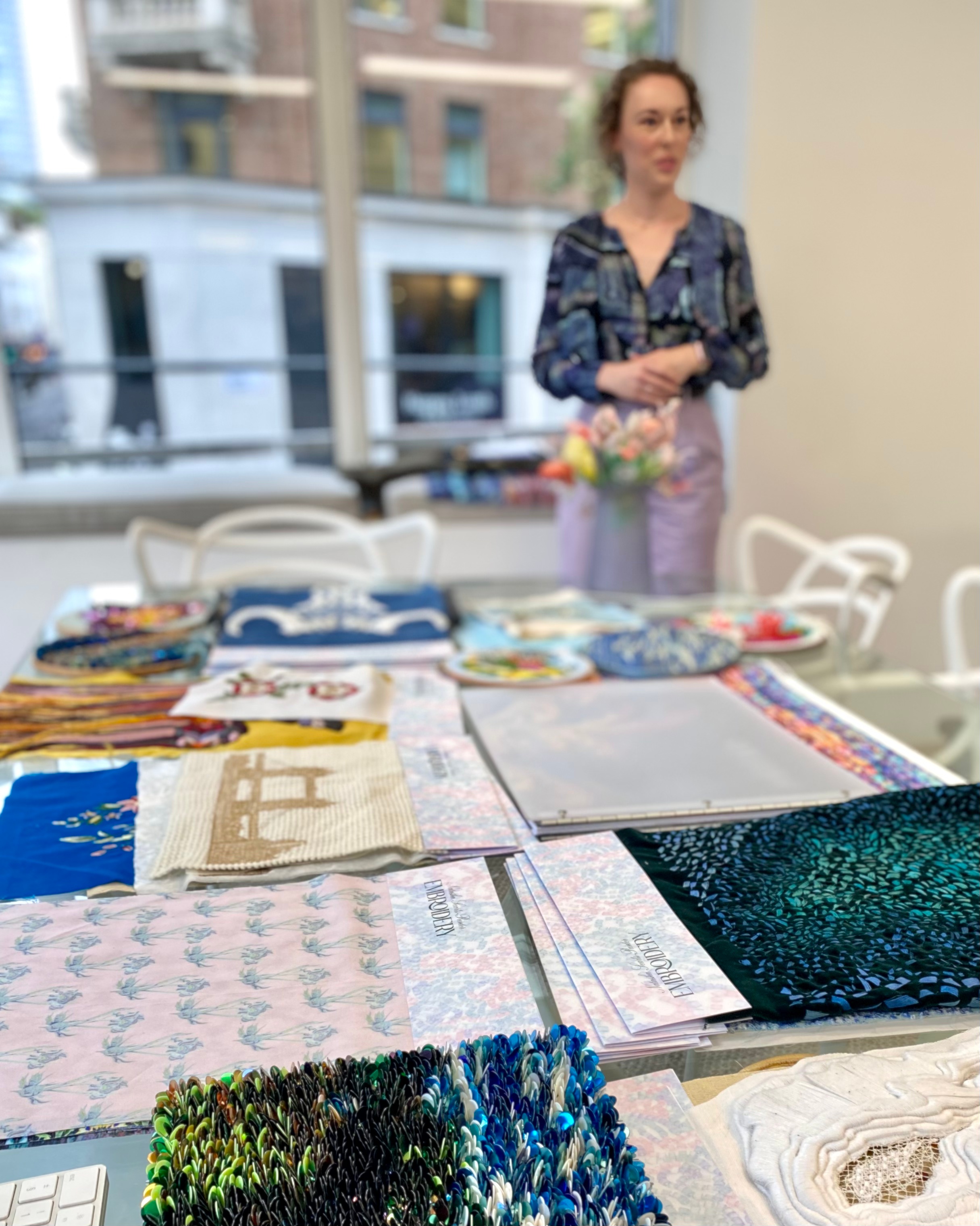 Natasha Searls-Punter stands in front of embroidery works laid across table